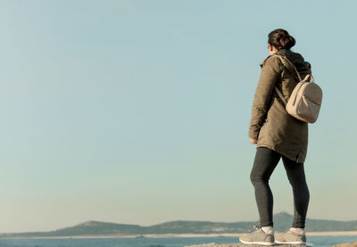 Woman with a backpack looks at the horizon over the sea