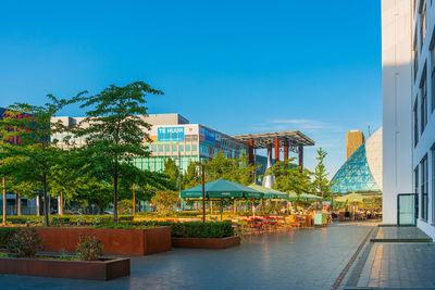 Buildings by swimming pool in city against clear blue sky