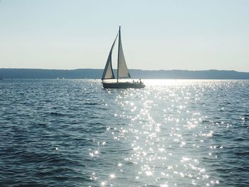 Sailboat sailing on sea against clear sky