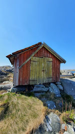 Old house on field against clear blue sky