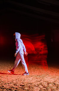 Full length side view of man standing against red umbrella at night