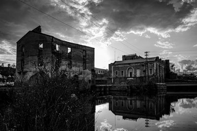 Reflection of buildings on river against sky in city