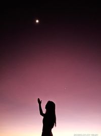 Silhouette man and woman standing against sky during sunset