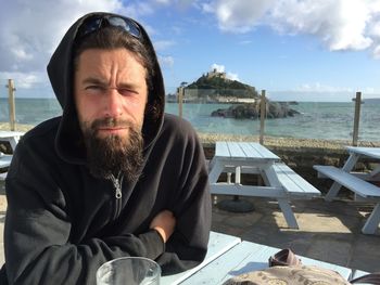 Man sitting by sea against sky