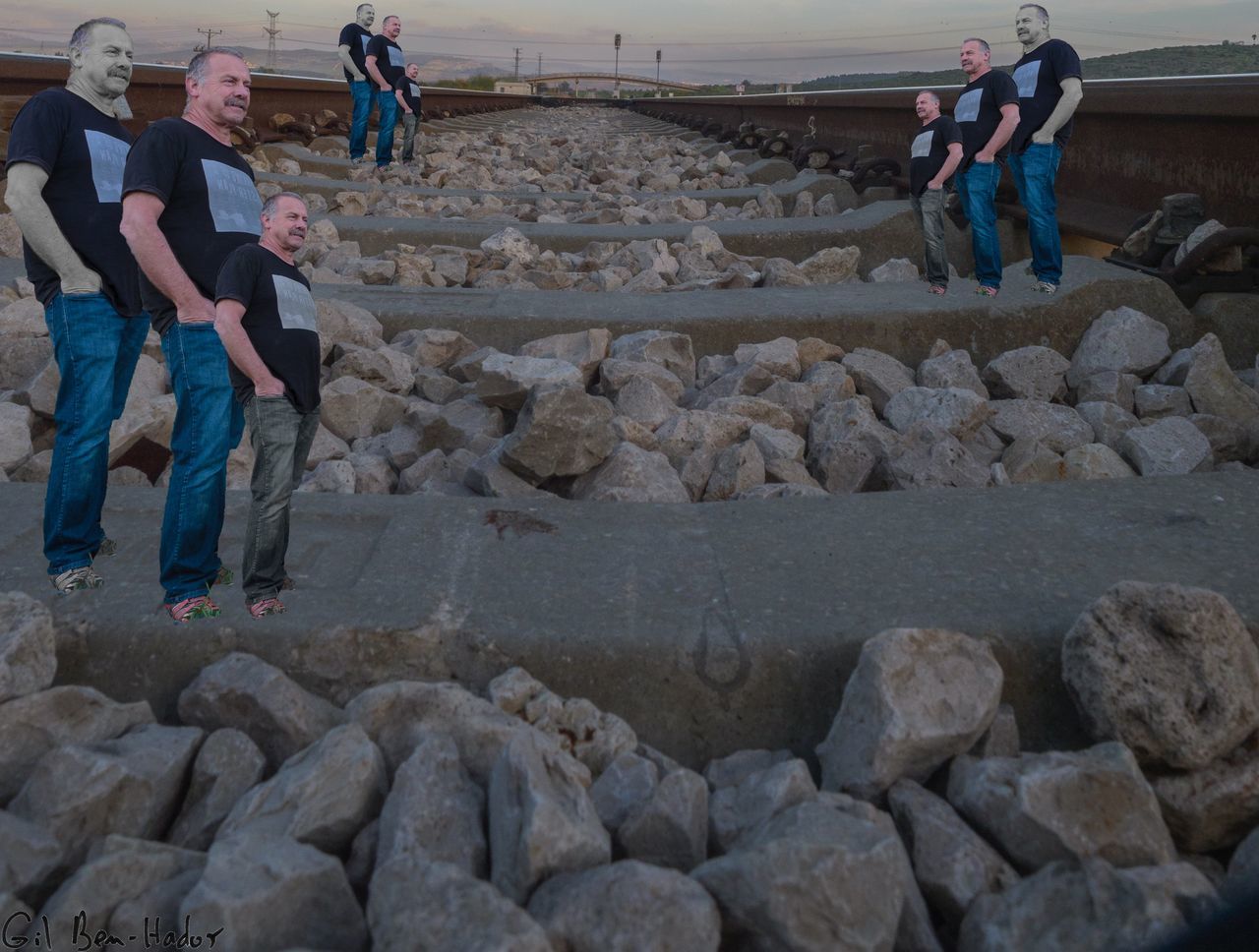 REAR VIEW OF PEOPLE STANDING AT SHORE