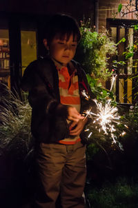 Full length of boy holding sparkler at night
