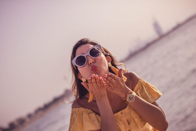 Woman blowing kiss while standing at beach