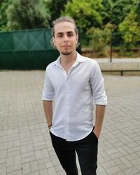 Portrait of young man standing on footpath