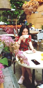 Pink flowers against woman drinking coffee at cafe