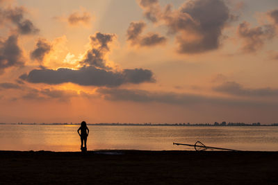 Silhouette man standing on beach against sky during sunset