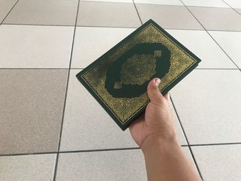 Low section of person holding umbrella on tiled floor