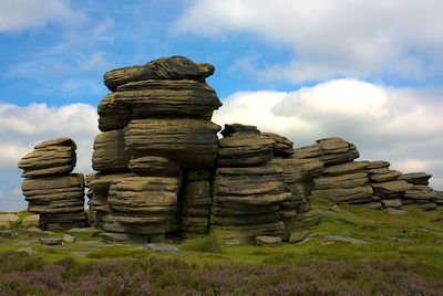 Stack of rocks on field against sky