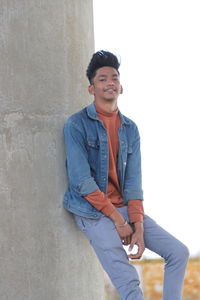 Portrait of young man standing against wall