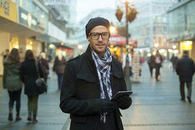 Portrait of young man standing on street in city
