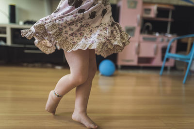 Swirling skirt of bare-legged 4 yr old girl dancing in playroom
