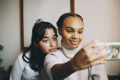 Teenage girls taking selfie with smartphone at home