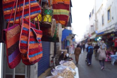 Close-up of multi colored shoulder bags hanging for sale in market