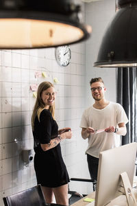 Portrait of young business people discussing ideas over adhesive notes in new office