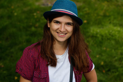 Portrait of a beautiful smiling young woman with brown hair wearing a hat and looking at camera 