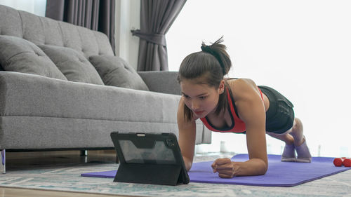 Young woman doing plank position at home