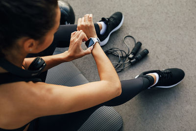 High angle view of woman using smartwatch while sitting in gym