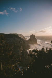 Rock formations by sea against blue sky