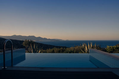 Swimming pool by sea against clear sky