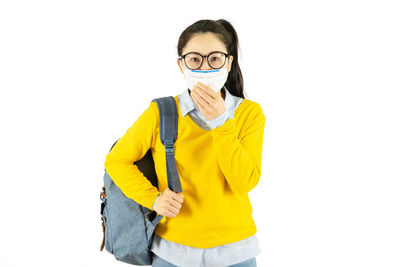 Portrait of young woman standing against white background