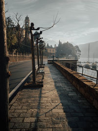 Footpath by street in city against sky