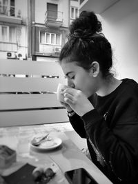 Side view of girl drinking coffee at cafe