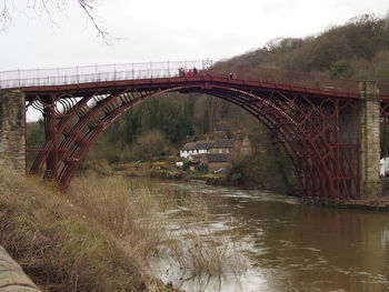 Arch bridge over river against sky