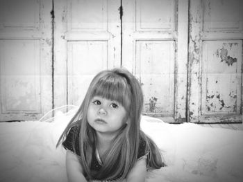 Close-up of girl sitting against wooden door