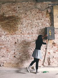 Rear view of woman standing against wall