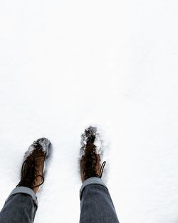 Low section of person wearing snow covered shoes