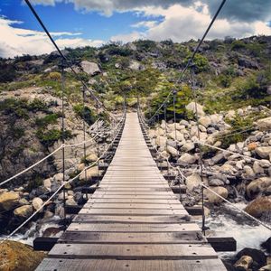 Footbridge amidst trees against sky