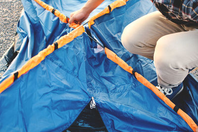 Low section of man crouching on blue tent