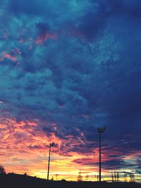 Low angle view of silhouette electricity pylon against dramatic sky