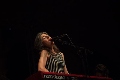 Young woman playing guitar at music concert