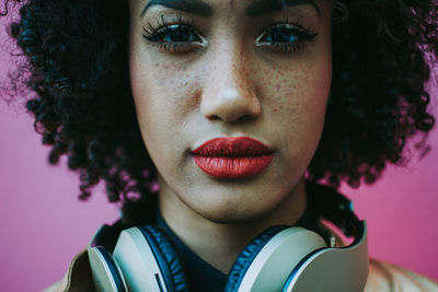 Close-up of young woman with frizzy hair against pink background