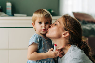 Mom kisses a little funny toddler girl.