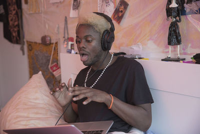 A young man wearing headphones with a laptop