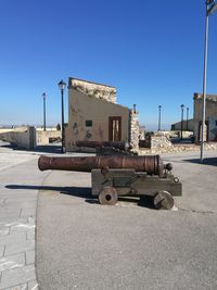 Old cannons on street against clear blue sky