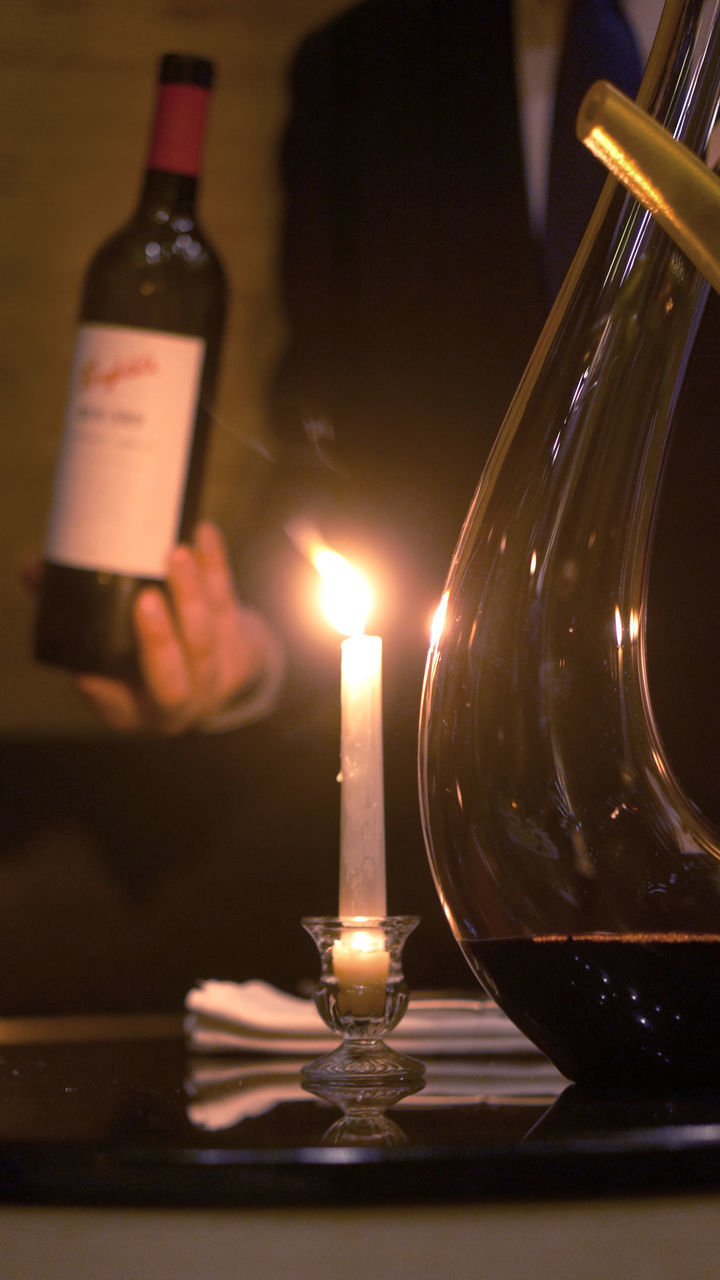 CLOSE-UP OF PERSON HAND ON ILLUMINATED CANDLE