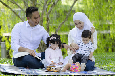 Full length of father with daughter sitting outdoors