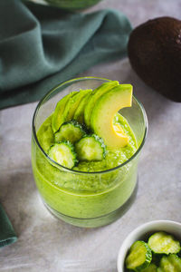 Healthy drink from cucumbers and avocados in a glass on the table vertical view