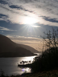 Scenic view of lake and mountains against bright sun