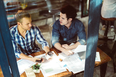 High angle view of colleagues discussing in cafe seen through window