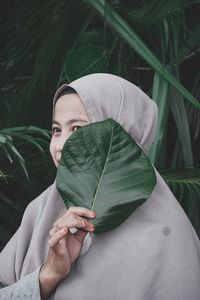 Portrait of young woman holding leaves