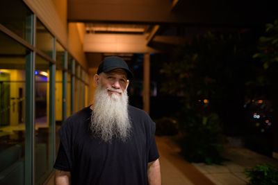 Portrait of man standing at illuminated shop