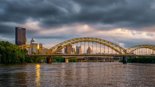 Arch bridge over river against cloudy sky